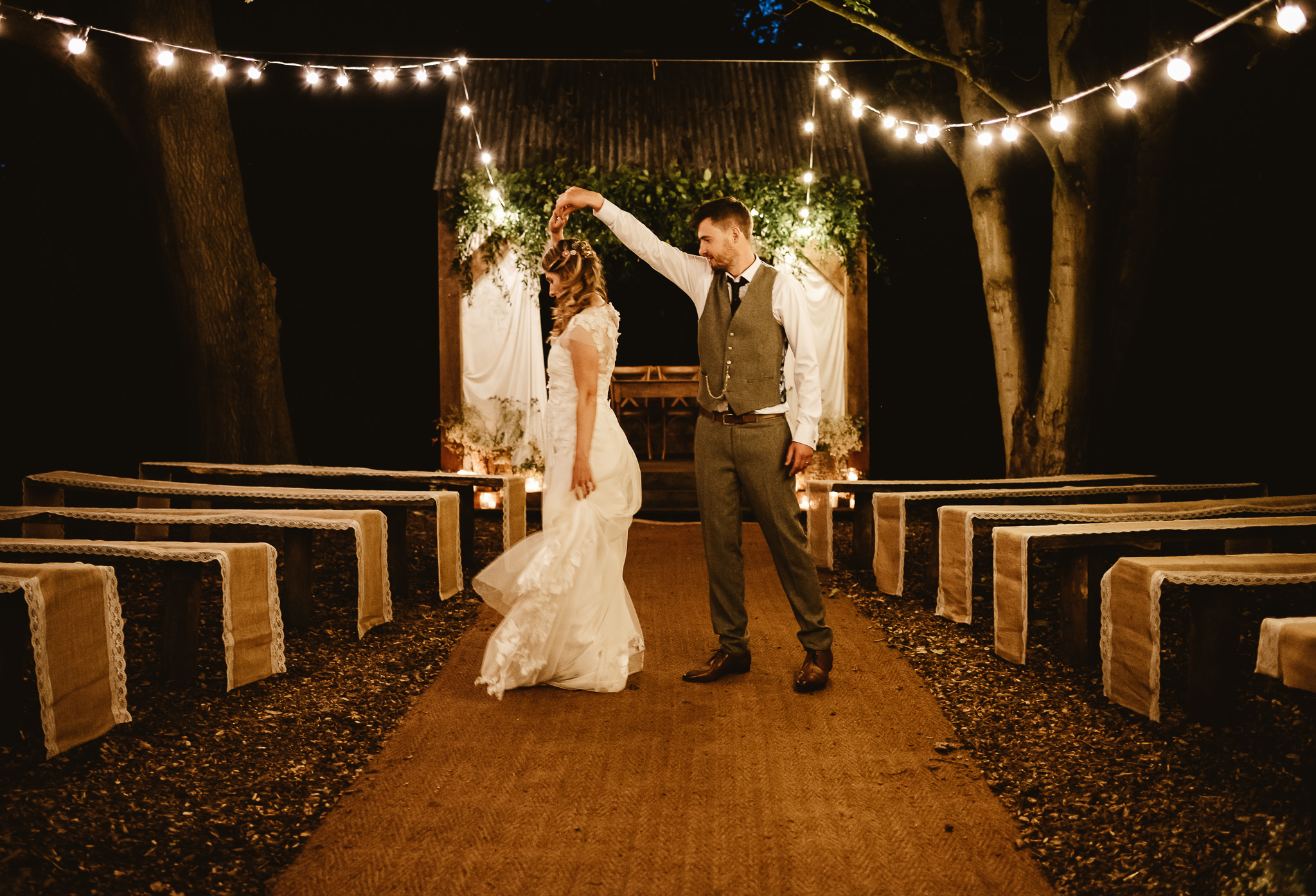 bride and groom dance underneath the fairy lights in the woods at their wedding