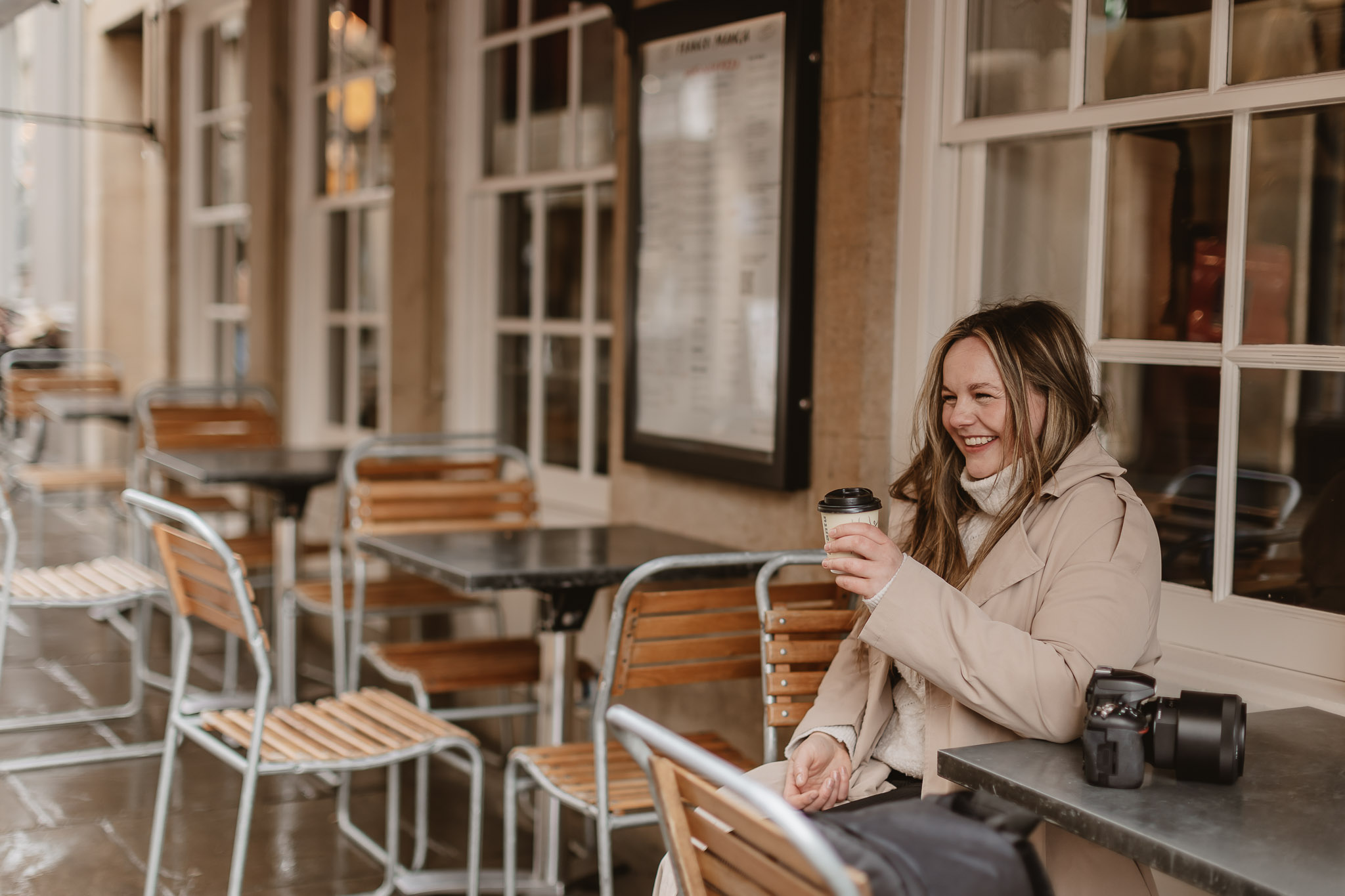 photographer laughing and drinking coffee outside a cafe in cambridge