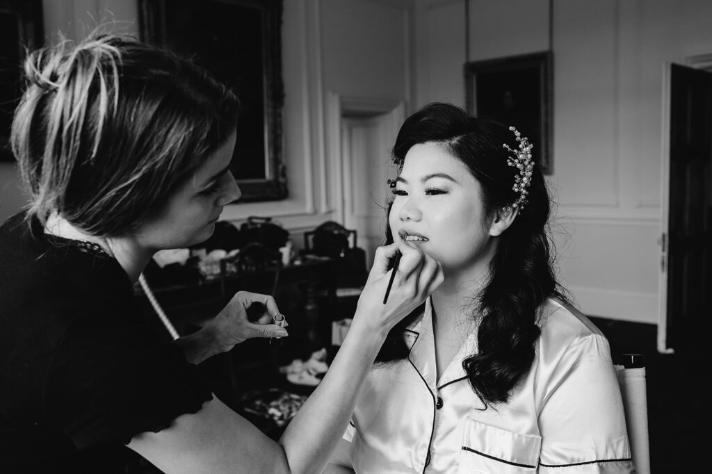 black and white image of bride getting lip stick put on