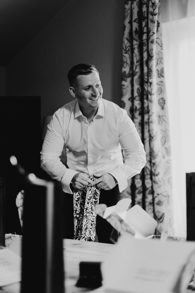 black and white image of groomsmen putting on his socks smiling