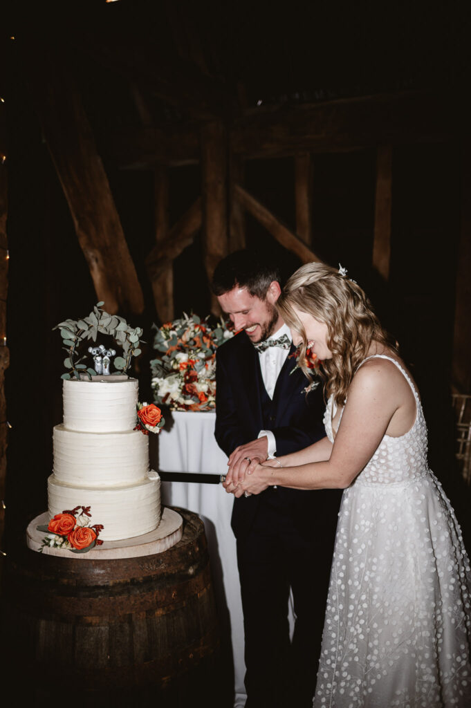 bride and groom cutting wedding cake and smiling