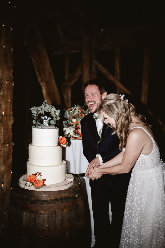 bride and groom cutting wedding cake and smiling