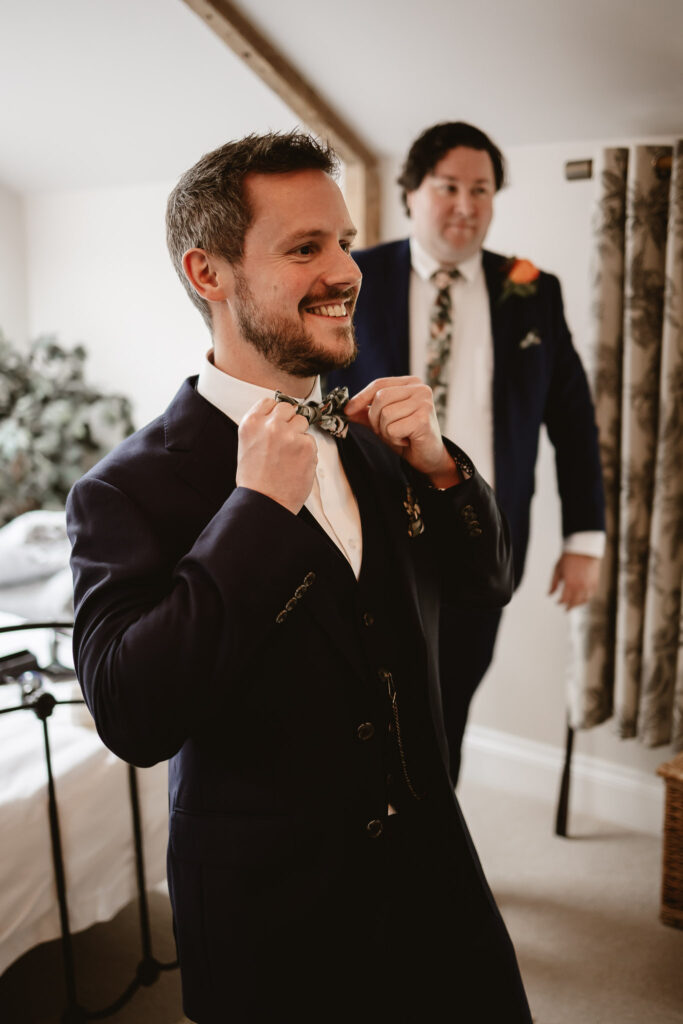 groom smiling and holding his coloured bowtie