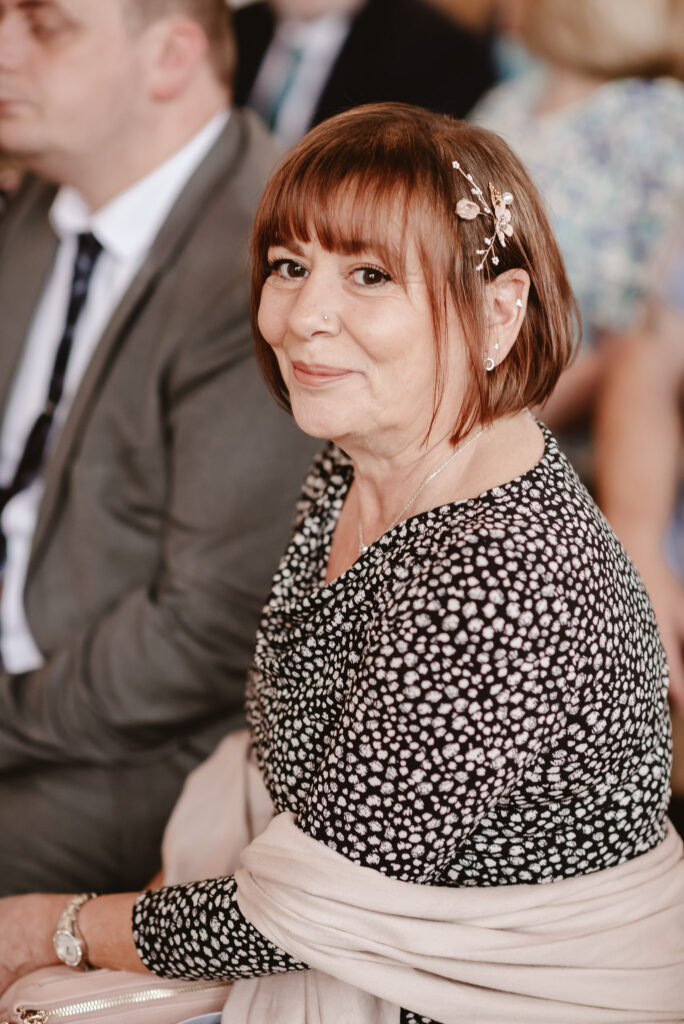 wedding guest with a hair piece and smartly dressed smiling at looking at the camera