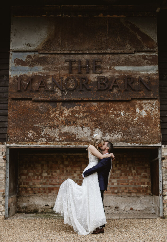 groom lifting bride and kissing outside wedding venue