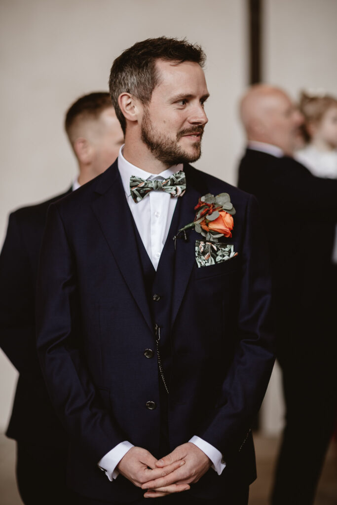 groom holding his hands and looking down the aisle 