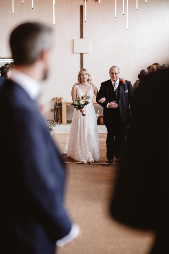 bride and father walking down the aisle towards the groom