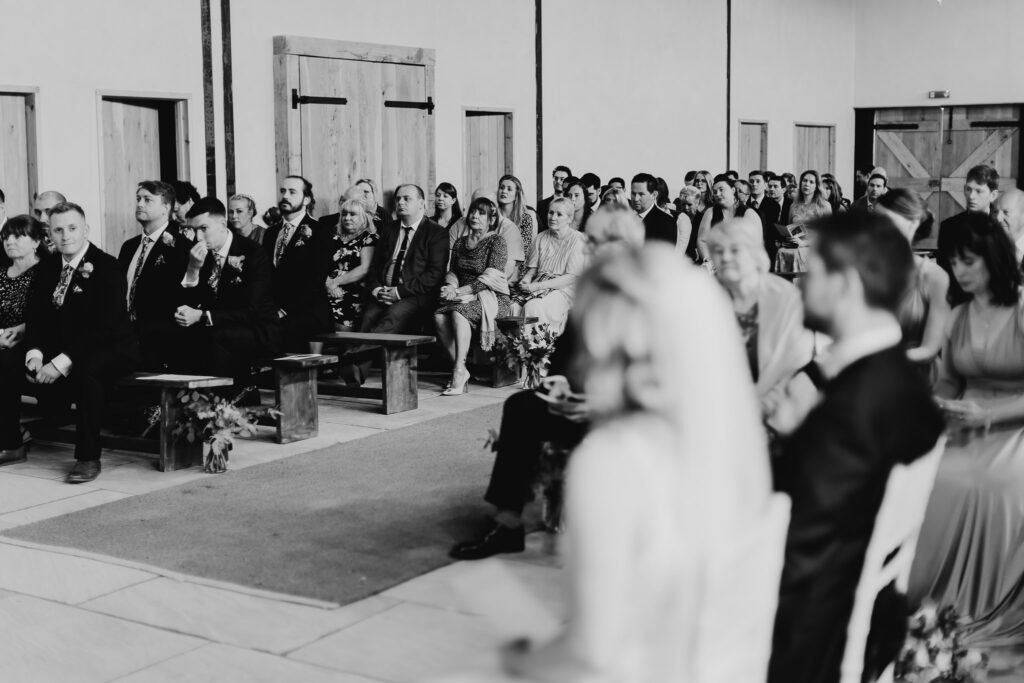 black and white image of wedding guests with the bride and groom sitting down