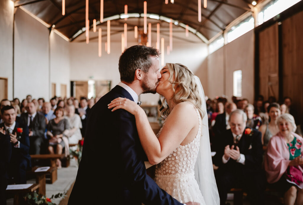 bride and groom kissing after the wedding ceremony in front of their guests 