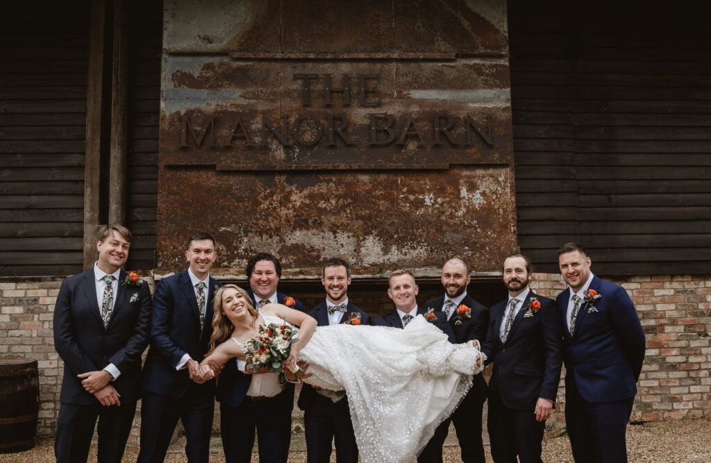 Groomsmen lifting the bride and smiling