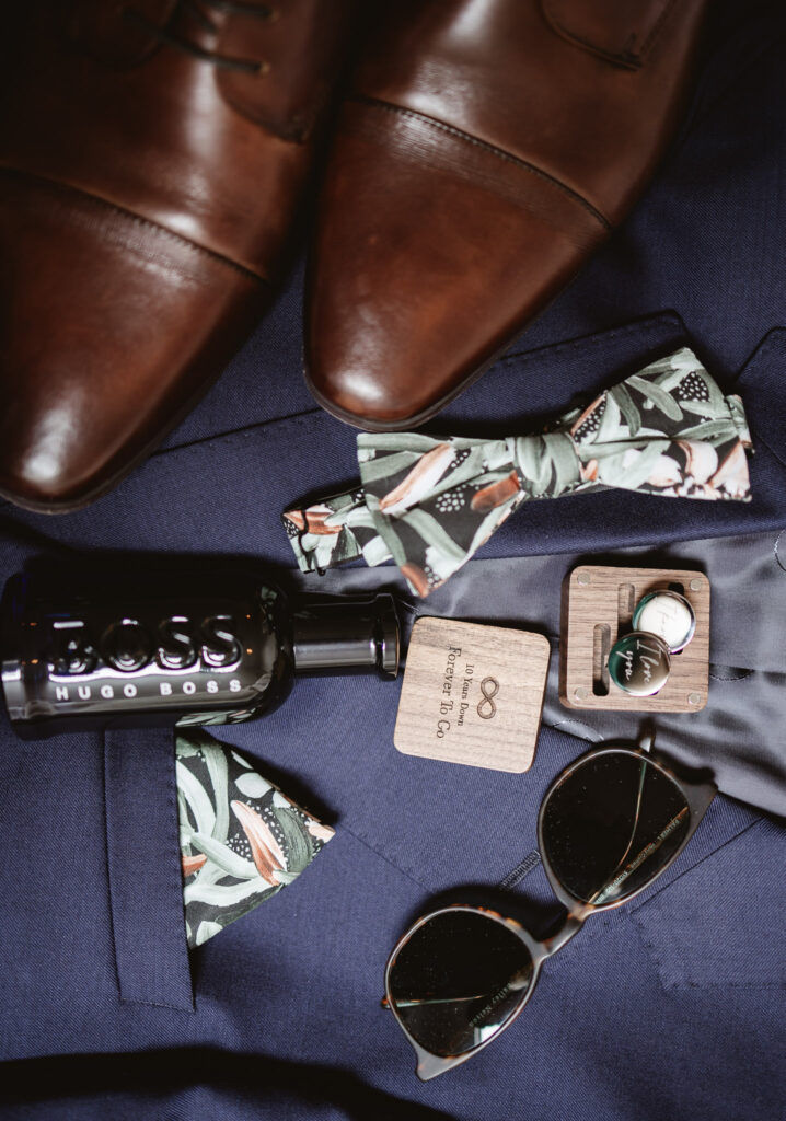 groom wedding details, shoes, sunglasses, bowtie, aftershave and pocket watch.