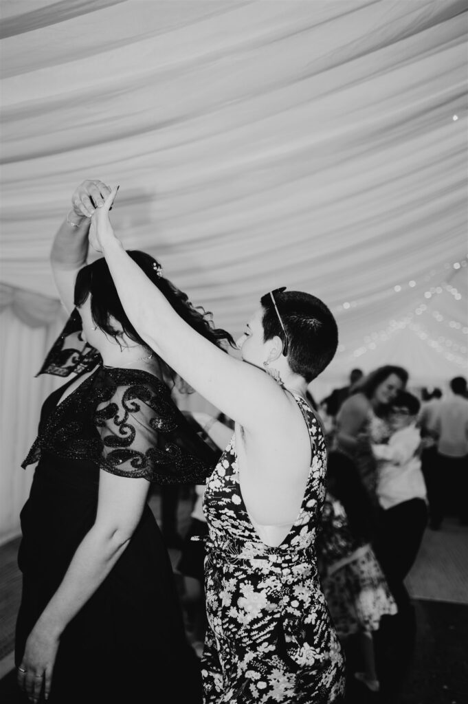 black and white image of bridesmaid and friend dancing during the wedding reception  