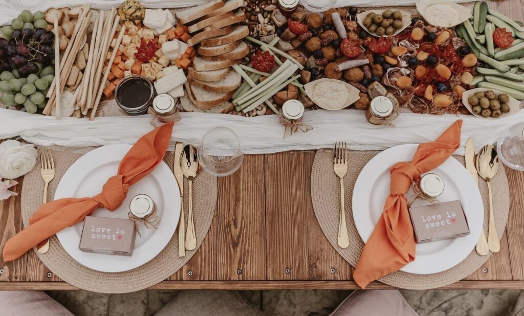 wooden table with a colourful spread of food with glassware