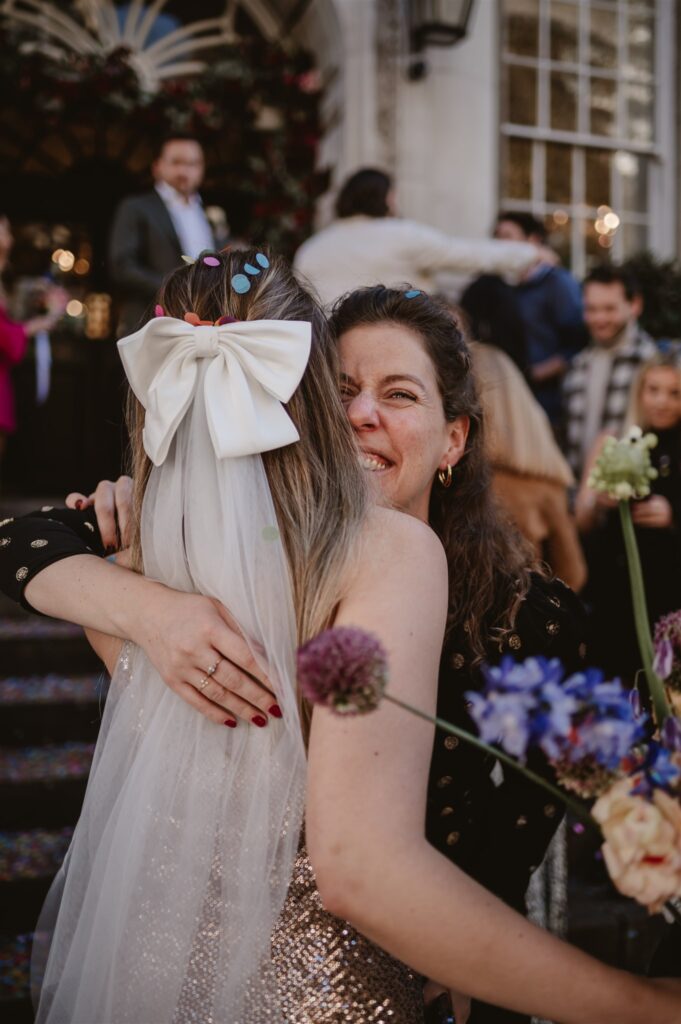 guest hugs bride with confetti in her hair