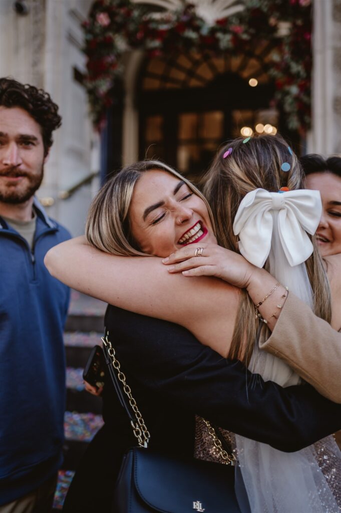 guest hugs bride with confetti in her hair