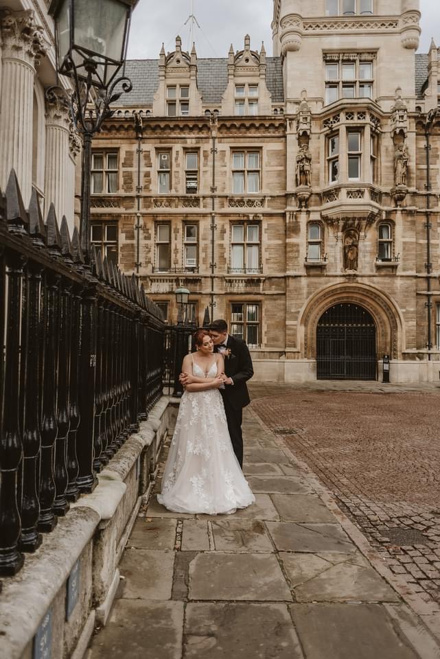 groom whispering into brides ear in the middle of Cambridge city