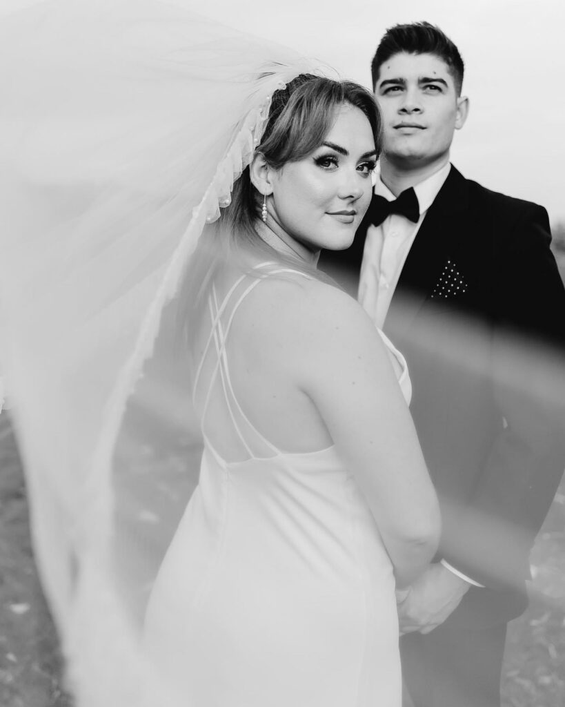 black and white image of bride and groom with the vail covering the lens